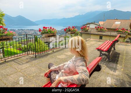 Femme assise au sommet du lac majeur en Suisse. Banc suisse avec vue aérienne depuis Orselina de Locarno et Ascona sur le mont Cardada. Lac majeur Banque D'Images