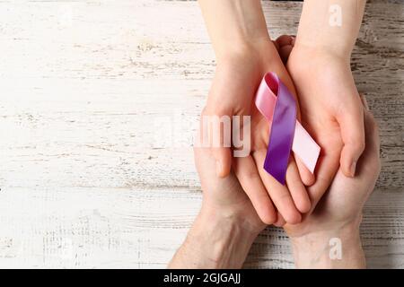 Mains avec ruban coloré sur fond en bois blanc. Concept de sensibilisation au cancer de la thyroïde Banque D'Images