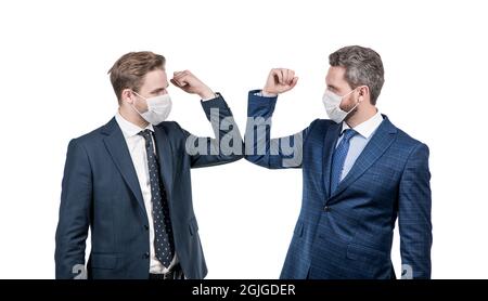 les hommes d'affaires en masque se cognent les coudes au lieu de serrer les mains pour éviter le contact, salutation d'affaires. Banque D'Images