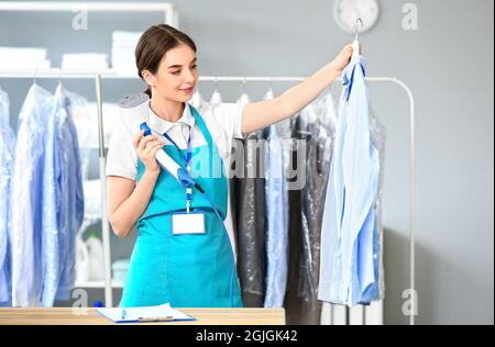 Femme travaillant à la vapeur des vêtements dans les nettoyeurs à sec modernes Banque D'Images