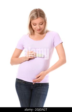Jeune femme enceinte avec des pilules d'acide folique sur fond blanc Banque D'Images