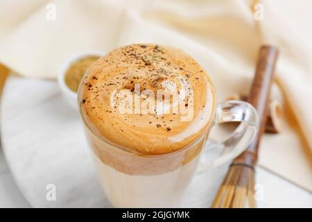 Tasse en verre de délicieux Dalgona hojicha latte sur table, gros plan Banque D'Images