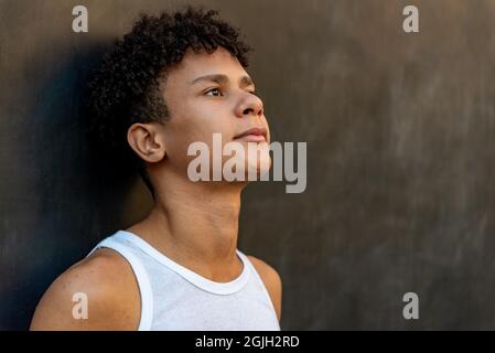 Afro latin homme adolescent contre un mur, regardant vers le haut. Banque D'Images