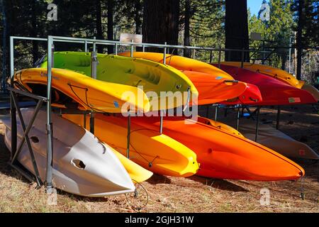 VILLAGE INCLINÉ, NV –11 APR 2021- des casiers de kayaks et planches de surf colorés dans les bois sur la rive du lac Tahoe. Banque D'Images