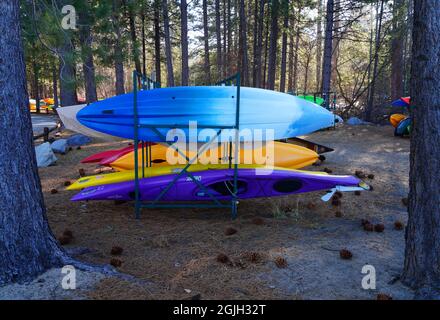 VILLAGE INCLINÉ, NV –11 APR 2021- des casiers de kayaks et planches de surf colorés dans les bois sur la rive du lac Tahoe. Banque D'Images