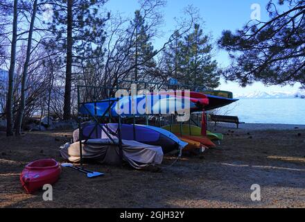 VILLAGE INCLINÉ, NV –11 APR 2021- des casiers de kayaks et planches de surf colorés dans les bois sur la rive du lac Tahoe. Banque D'Images