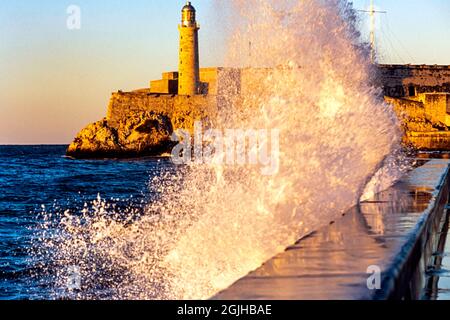 Vagues se brisant sur le Malecon, avec le phare de Faro Castillo del Morro, la Havane, Cuba Banque D'Images