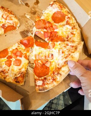 Une tranche de pizza dans votre main, vue du dessus. Banque D'Images