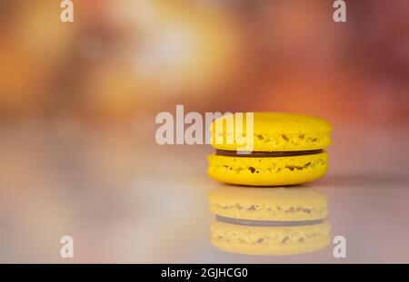 Un seul jaune délicieux macarons, un célèbre dessert français multicolore. Arrière-plan flou Banque D'Images