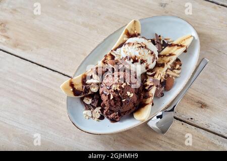 Au-dessus de la petite banane douce dessert avec des boules de crème glacée à la vanille et au chocolat servies sur une table en bois Banque D'Images