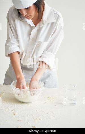 femme dans l'uniforme du chef soupir la pâte de farine travaillant dans la cuisine Banque D'Images