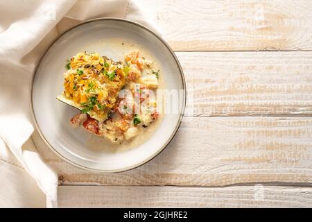 Portion de courgettes cuites farcies de légumes et de parmesan avec une sauce de tomate et de feta sur une assiette et une table en bois rustique clair, co Banque D'Images