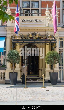 Portier en uniforme situé à l'extérieur de l'entrée principale de l'hôtel Connaught, Mayfair, Londres, Angleterre, Royaume-Uni Banque D'Images