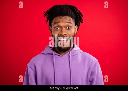 Portrait d'attrayant gai surpris brunet gars portant le sweat à capuche bonne nouvelle réaction isolée sur fond rouge vif Banque D'Images