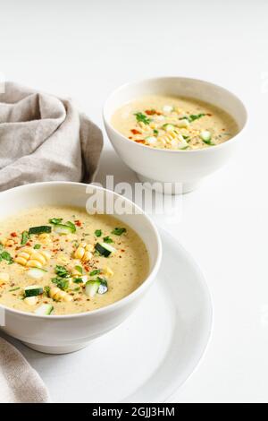 Deux bols de maïs crémeux et de chaudrée de courgettes recouverts de persil et de poivre de Cayenne. Banque D'Images