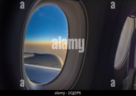 Vue sur le lever du soleil depuis un avion à fenêtre Banque D'Images