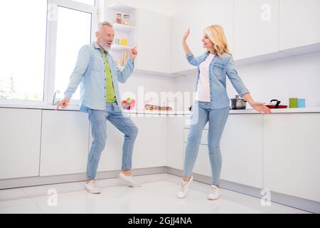 Grand format photo gaie sourire bonne humeur couple mûr dansant dans la cuisine insouciante appréciant le temps libre de week-end Banque D'Images