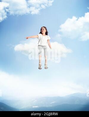 Œuvres d'art créatives, collage avec petite fille belle assise sur le nuage blanc et volant au-dessus de la forêt, paysage de la nature. Concept de l'enfance, du bonheur Banque D'Images