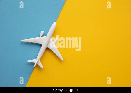 au-dessus de la tête, poser à plat un avion de passagers blanc sur un fond bleu et jaune vif Banque D'Images