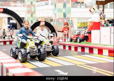 Moscou, Russie, 28 mai 2021 - les petits enfants heureux garçon et fille s'amuser à monter une petite voiture électrique sur le terrain de sport dans un terrain de jeux pour les divertissements. chi Banque D'Images