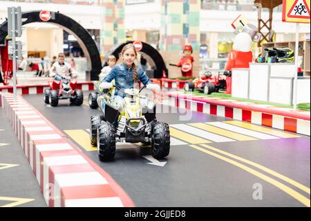 Moscou, Russie, 28 mai 2021 - Little Happy Kid girl fun à bord d'une petite voiture électrique sur un terrain de sport dans une aire de jeux pour les divertissements. Les enfants se débarrassent Banque D'Images