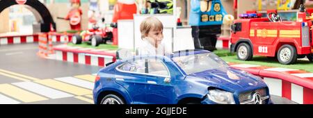 Moscou, Russie, 28 mai 2021 - un petit garçon joyeux, amusant, à conduire une petite voiture électrique sur un terrain de sport dans une aire de jeux pour les divertissements. Enfants ridi Banque D'Images