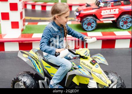 Moscou, Russie, 28 mai 2021 - Little Happy Kid girl fun à bord d'une petite voiture électrique sur un terrain de sport dans une aire de jeux pour les divertissements. Les enfants se débarrassent Banque D'Images