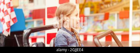 petite fille heureux amusement de l'enfant à cheval une petite voiture électrique sur le terrain de sport dans un terrain de jeux pour les divertissements. enfants à cheval dans le jouet auto dans un amus Banque D'Images