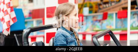 petite fille heureux amusement de l'enfant à cheval une petite voiture électrique sur le terrain de sport dans un terrain de jeux pour les divertissements. enfants à cheval dans le jouet auto dans un amus Banque D'Images