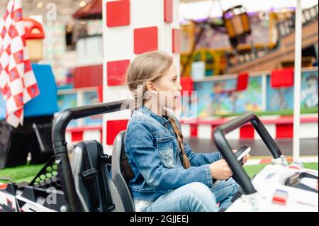 Moscou, Russie, 28 mai 2021 - Little Happy Kid girl fun à bord d'une petite voiture électrique sur un terrain de sport dans une aire de jeux pour les divertissements. Les enfants se débarrassent Banque D'Images