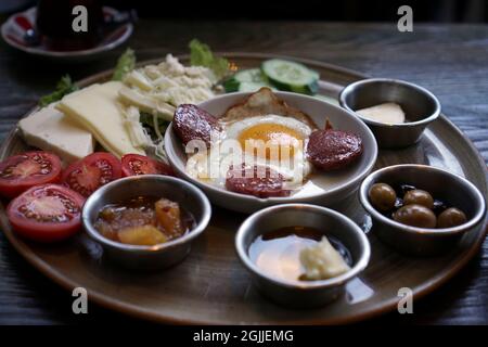 Petit déjeuner turc prêt à manger. Il y a des oeufs avec des saucisses, des tomates en tranches et des concombres, du miel, de la confiture, des olives à la table. Banque D'Images