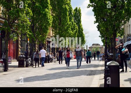 HALIFAX. WEST YORKSHIRE. ANGLETERRE. 05-29-21. Cornmarket dans le centre-ville. Les acheteurs marchant au bord des arbres sous le soleil de l'après-midi. Banque D'Images