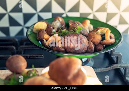 Des boulettes et des champignons dans un bol vert sur la grille d'un poêle à gaz Banque D'Images