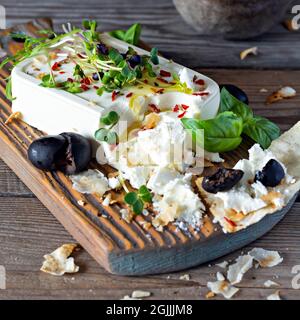 Un morceau de feta frais (paneer) avec des olives, des herbes, des épices et des tranches de pain plat (tortilla, lavash, pitta, chapatti) sur une planche en bois et un d Banque D'Images