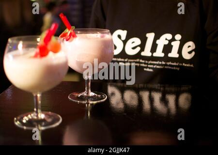 Cocktails de noix de coco verres sur la table avec un T-shirt Selfie en arrière-plan. Banque D'Images