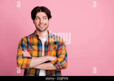 Photo de charmant joli jeune gentleman port tenue à carreaux mains croisées regard vide espace souriant isolé couleur rose fond Banque D'Images