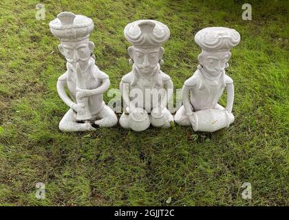Trois idoles de couleur blanche en forme humaine qui se sitaient sur l'herbe et jouent des instruments de musique classiques Banque D'Images