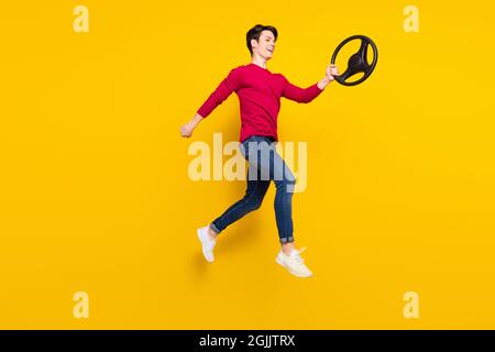 Photo pleine longueur de doux choqué jeune gentleman porter rouge chandail saut tenant le volant isolé couleur jaune arrière-plan Banque D'Images
