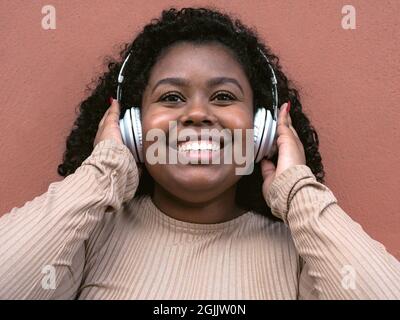 Bonne fille afro latine ayant plaisir à écouter de la musique avec le sans fil casque d'extérieur Banque D'Images