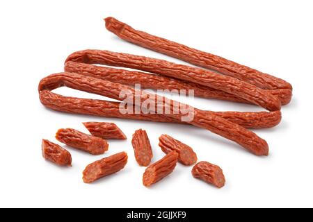 Des morceaux entiers et des morceaux de saucisses de cabanossi fumées pour un en-cas isolé sur fond blanc Banque D'Images