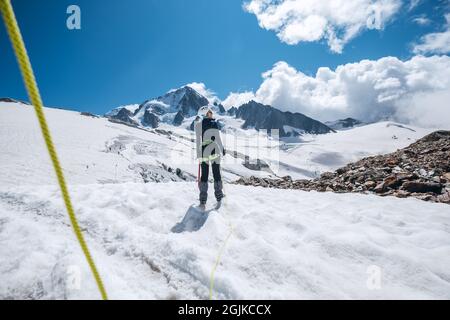 Jeune femme Portrait de dos membre de l'équipe de corde sur l'acclimatation jour vêtements d'alpinisme habillés marchant par des pentes enneigées dans le harnais d'escalade et Banque D'Images