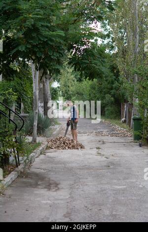 Zatoka, Odessa, Ukraine - 1 septembre 2021 Gardener enlève les feuilles avec un aspirateur de jardin Banque D'Images