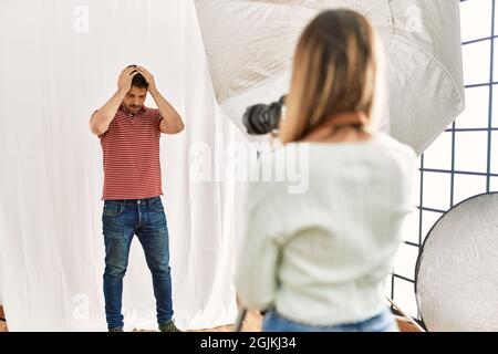 Femme photographe parlant des photos de l'homme posant comme modèle dans le studio de photographie souffrant de maux de tête désespérés et stressés parce que la douleur et migra Banque D'Images