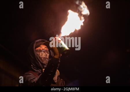 Bogota, Colombie. 10 septembre 2021. Un manifestant allume une bombe de peinture en feu alors que le poste de police de Villa Luz CAI était torturé Javier Ordoñez par des policiers le 9 septembre 2020, plus tard le même jour plusieurs postes de police ont été vandalisés et brûlés à la suite de la mort d'Ordoñez, et le nombre de morts de 12 autres personnes qui sont mortes de l'utilisation d'armes à feu par la police et de cas de brutalité la même nuit. Le 9 septembre 2021 à Bogota, Colombie. Crédit : long Visual Press/Alamy Live News Banque D'Images