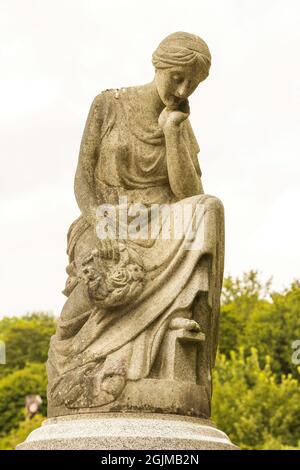 Une statue en pierre d'une femme assise avec sa tête reposant sur sa main, sur une tombe du cimetière d'Arnos Vale, Bristol UK, 02-09-2021. Banque D'Images