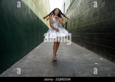 Une adolescente asiatique tourne en robe de fête dans une allée vert foncé Banque D'Images