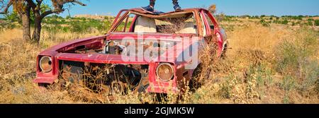 Voiture de style vintage abandonnée et de fard à sourcils sur un terrain agricole recouvert de plantes jaunes et d'herbe Banque D'Images