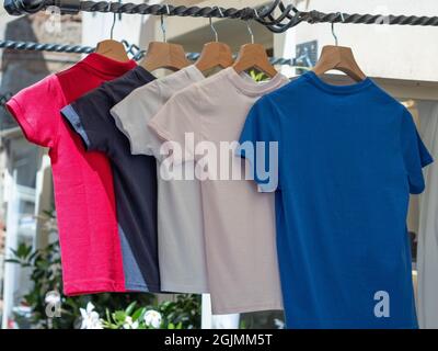 Groupe de T-shirts de couleur pour enfants suspendus à l'extérieur d'un magasin de vêtements. Banque D'Images