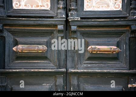 Ancienne maison néoclassique Faded cyprès porte d'entrée en bois vert avec des grilles en fer artisanales et une ancienne poignée en laiton à Galaxidi, Phosis Grèce. Banque D'Images