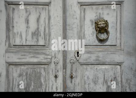 Ancienne porte d'entrée en bois gris patiné avec une ancienne tête de lion en laiton à Galaxidi, Phosis Grèce. Banque D'Images
